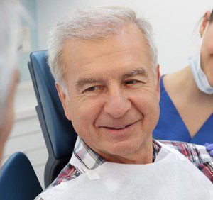 Older male patient smiling in dental chair