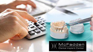 Cost of Dental Implants, calculator and patient's model with implant bridge